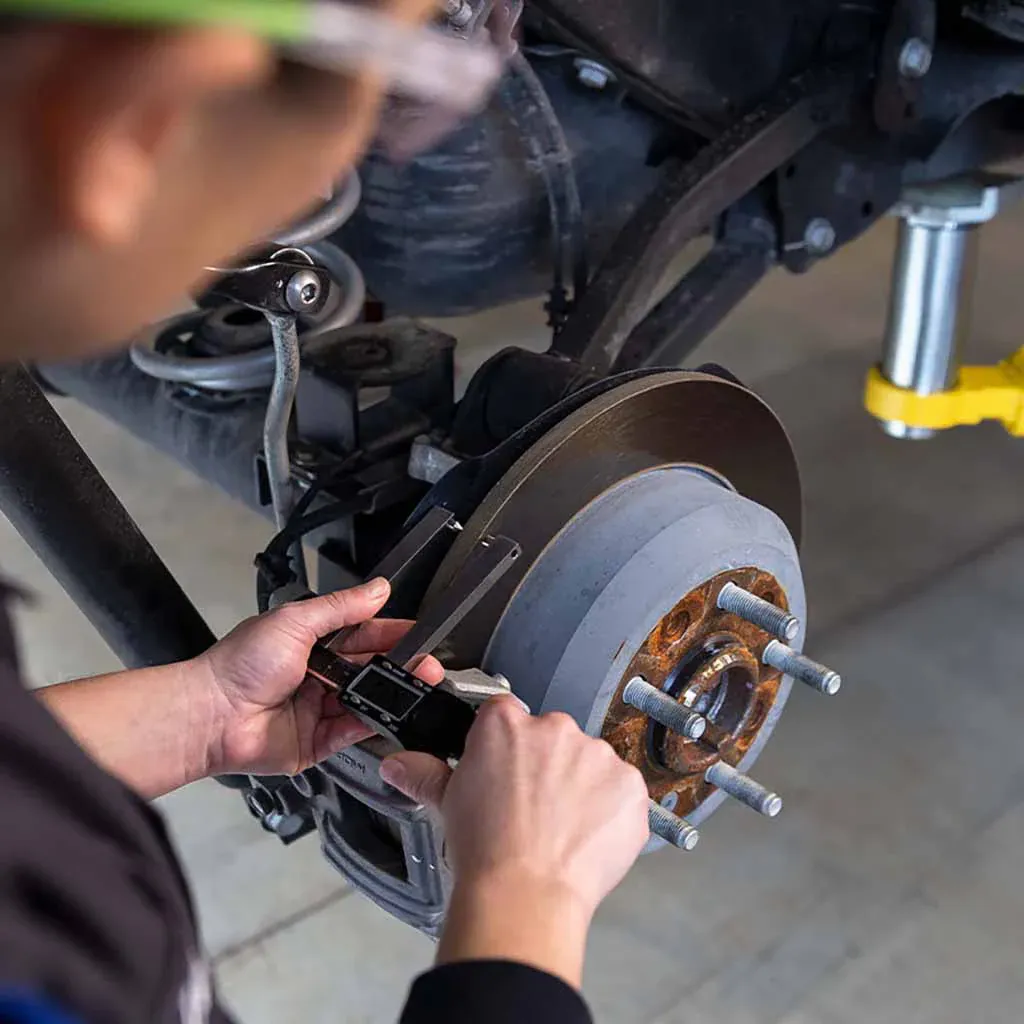 Technician inspecting a vehicle brake system during a mobile visit in San Antonio